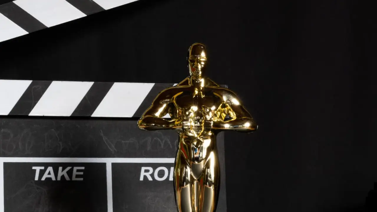 Estatueta do Oscar em frente a um claquete de cinema