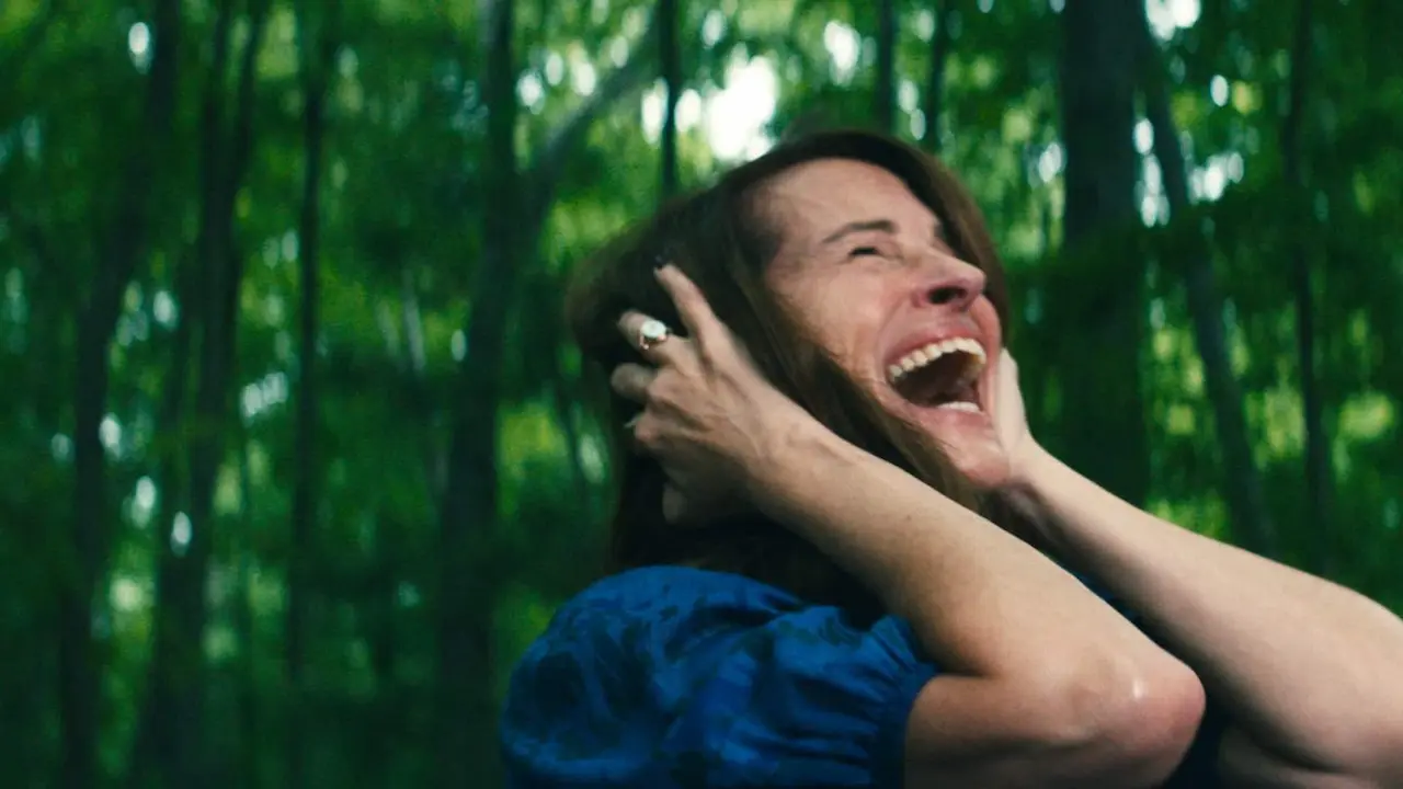 Mulher branca com vestido azul em uma floresta com as mãos no ouvido gritando de dor
